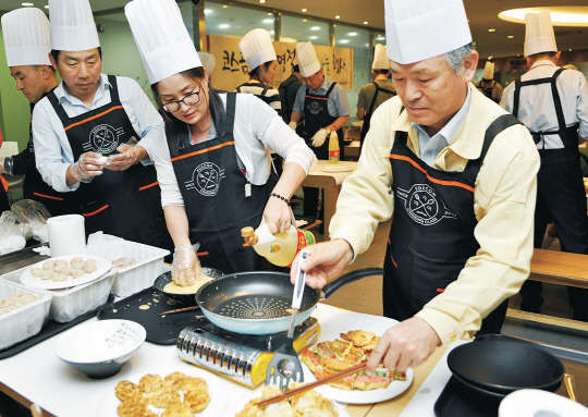 정연대 코스콤 사장(오른쪽)을 비롯한 임직원들이 지난 23일 오후 서울 여의도 본사 구내식당에서 저소득가정을 위한 전을 부치고 있다.    코스콤 제공
